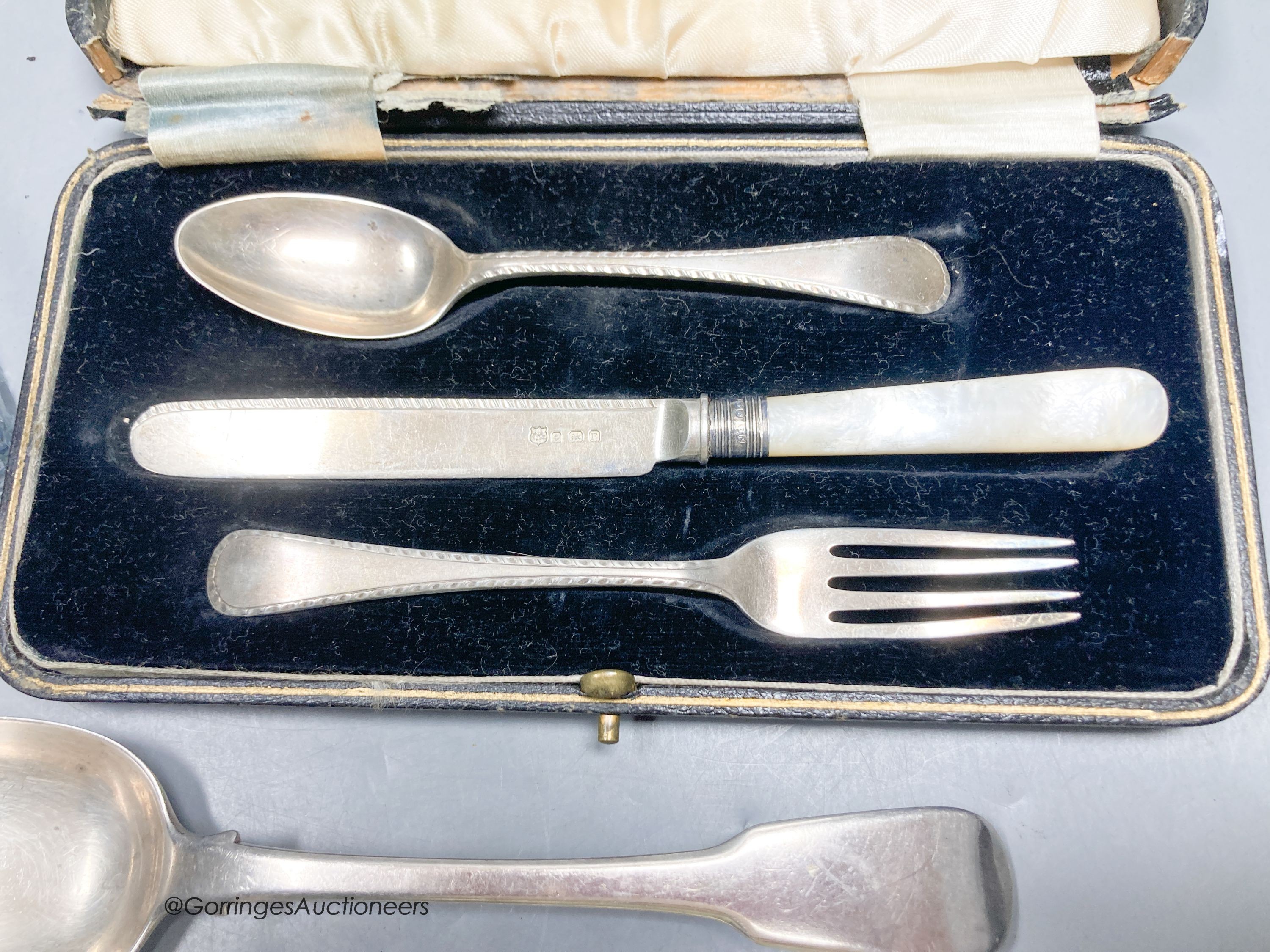 A silver mounted glass inkwell, two silver spoons and a silver Christening set.